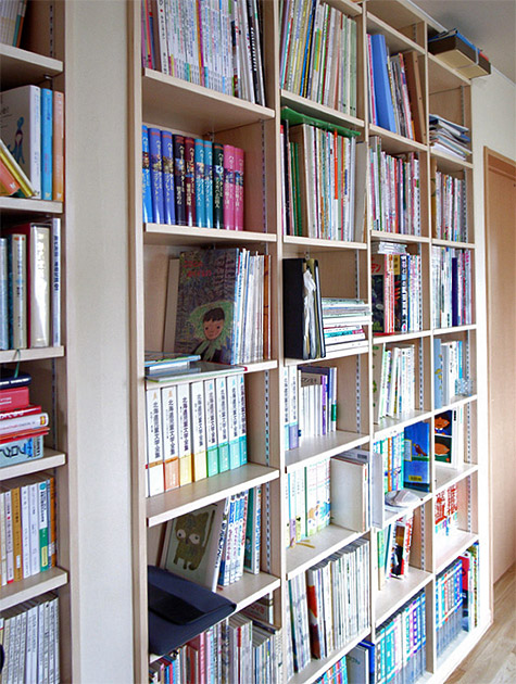階段を上った共有スペースの壁一面に設けられた造作本棚。両面になっており、壁裏のご主人の部屋にも同じ本棚がある。お子さんが小さい頃に読んで聞かせた本など、階段側は奥様のコレクション。裏面はご主人の本がずらりと並んでいる